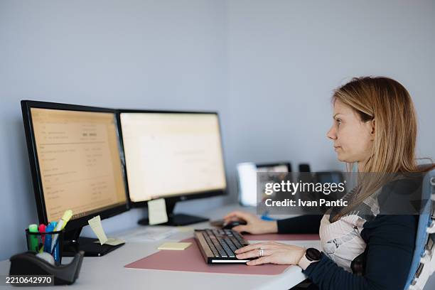 frau, die an zwei monitoren in einer home-office-umgebung arbeitet - kleines büro stock-fotos und bilder