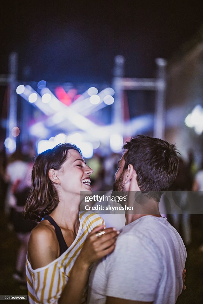 Young happy couple having fun on music concert at night.