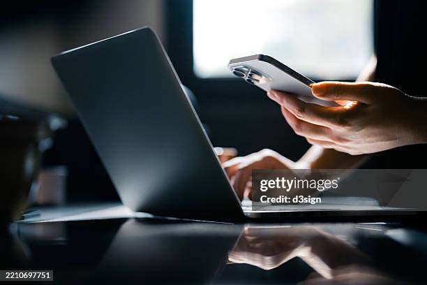 close-up shot of a woman using mobile device with two-factor authentication (2fa) security while logging in securely to her laptop. privacy protection, internet and mobile security - internet stockfoto's en -beelden