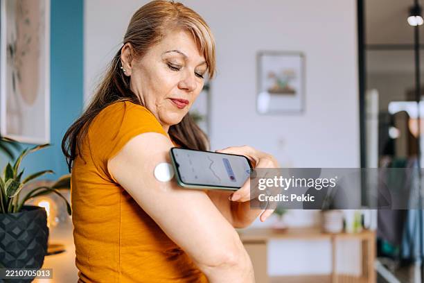 senior woman checking blood sugar level with smartphone - glucose stockfoto's en -beelden