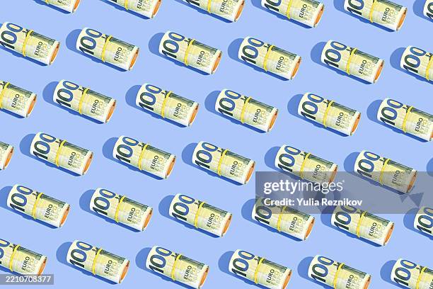 repeated rolls 100 euro banknotes on the blue background - geld stock-fotos und bilder