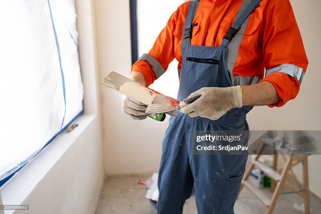 Worker applying putty to a wall during a room renovation