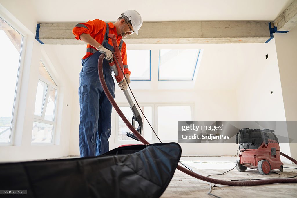 Un profesional de la construcción está preparando la lijadora de pared de jirafa en un espacio limpio y moderno