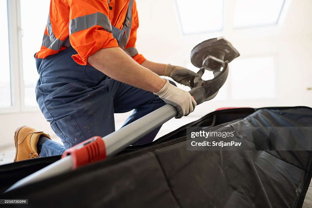 A construction professional is preparing the giraffe wall sander