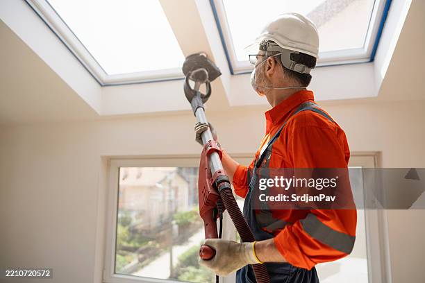 skilled craftsman sanding walls beneath skylight with sanding giraffe tool - painters putty stock pictures, royalty-free photos & images