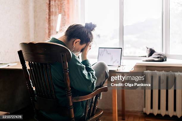 stressed businesswoman looking at declining stock market chart on laptop - agotamiento fotografías e imágenes de stock