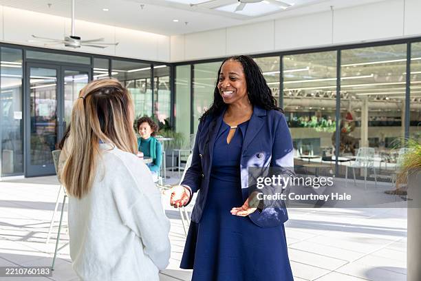 teachers stop to talk while walking to class on modern campus - student union stock pictures, royalty-free photos & images