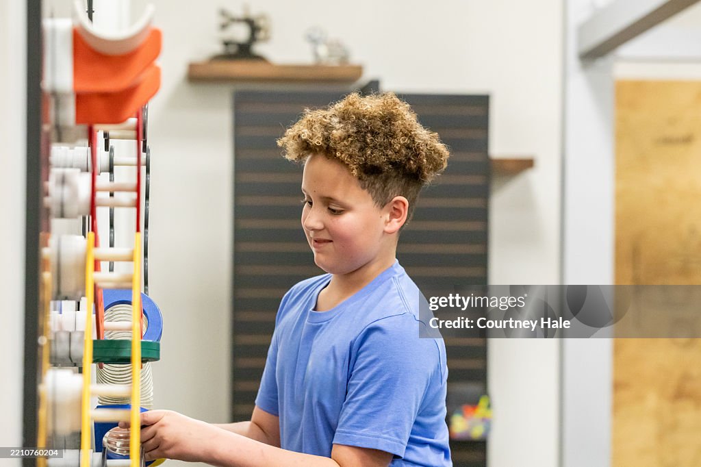 Little boy uses STEM educational toys while learning in modern classroom