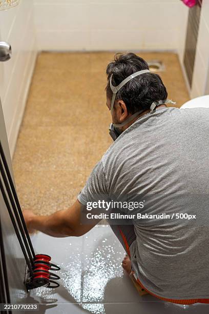 man wearing respiratory mask doing renovation view from behind - respiratory protection construction stock pictures, royalty-free photos & images
