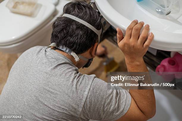 man wearing respiratory mask doing renovation view from behind - respiratory protection construction stock pictures, royalty-free photos & images