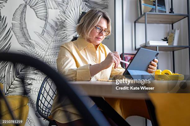 elderly graphic designer working from home with her digital tablet - electronic banking stock pictures, royalty-free photos & images