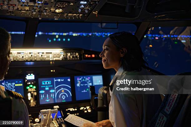 co-pilot smiles as she looks to the pilot sat next to her - night - flight-instruments stockfoto's en -beelden