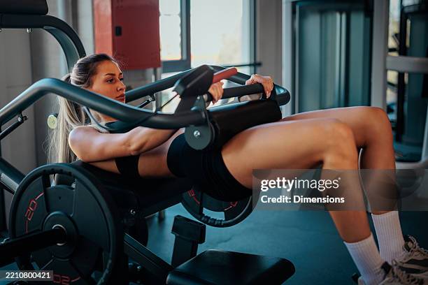 determined sportswoman performing hip thrusts on gym machine - hamstring machine stock pictures, royalty-free photos & images