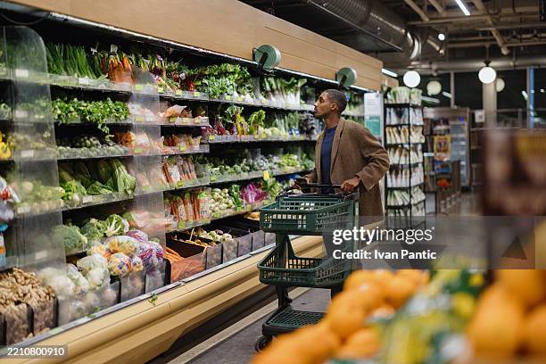 man shopping for fresh produce in a grocery store aisle - stormarknad bildbanksfoton och bilder