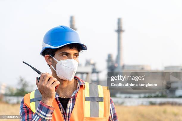 close-up of a male engineer wearing protective face mask with power plant background. - respiratory protection construction stock pictures, royalty-free photos & images