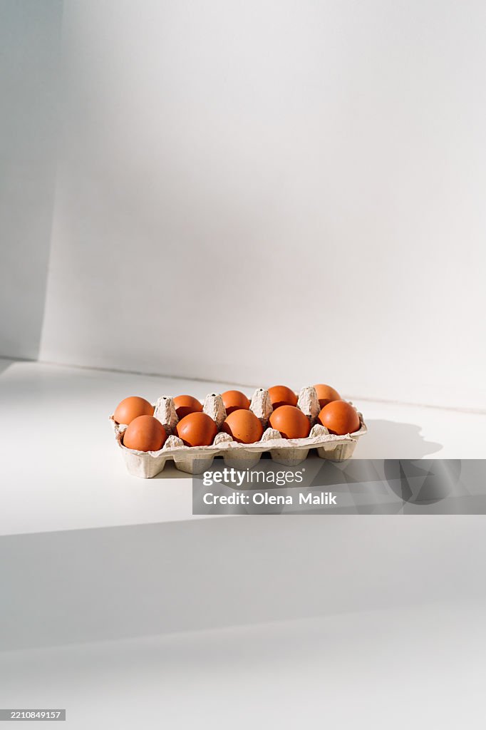 Tray of Brown Eggs Illuminated by Natural Light on a White Surface