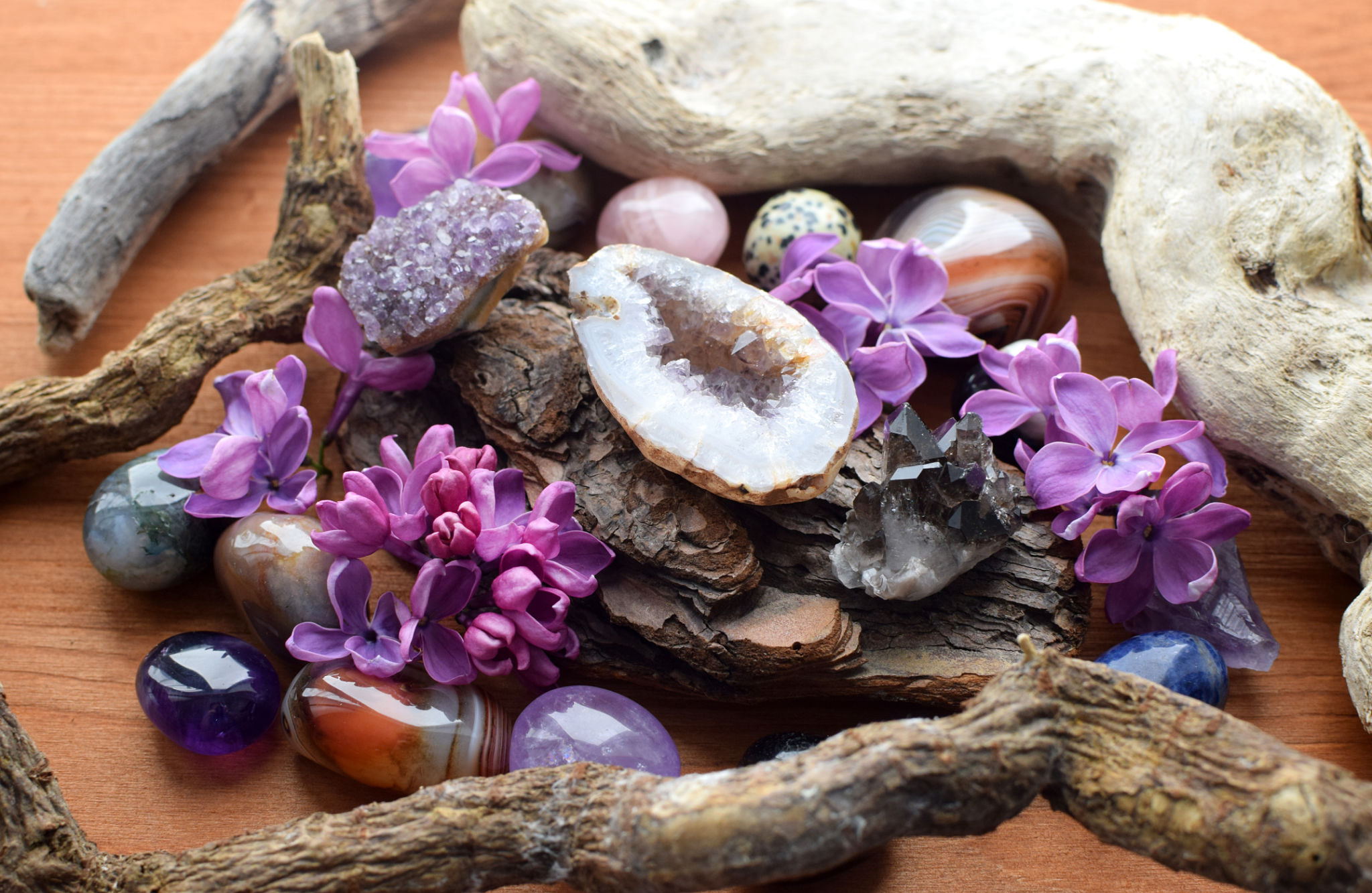 Beautiful geode of purple amethyst crystals on wooden background with lilac flowers Beautiful geode of purple amethyst crystals on wooden background with lilac flowers