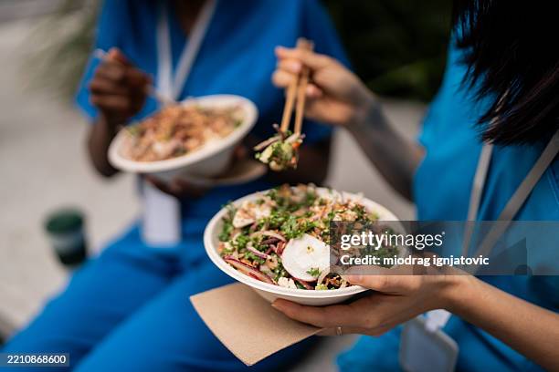 healthcare workers enjoying asian cuisine on outdoor lunch break - lunchpauze stockfoto's en -beelden
