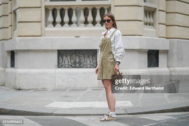 Diane Batoukina wears a white cotton blouse with a spread collar and voluminous balloon sleeves by Longchamp, styled under a sleeveless olive green...