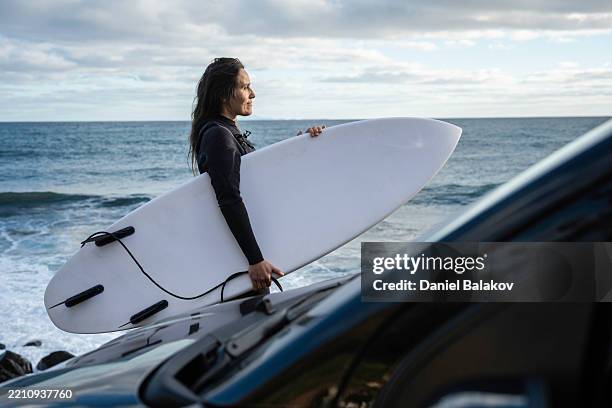surfer woman at sunrise with board near car at ocean beach - wetsuit stock pictures, royalty-free photos & images
