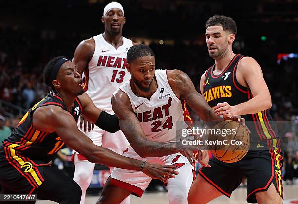 Haywood Highsmith of the Miami Heat grabs a rebound against Onyeka Okongwu and Georges Niang of the Atlanta Hawks during the fourth quarter of an NBA...