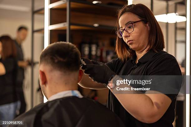young male client in a barber shop - black and white barbershop stock-fotos und bilder