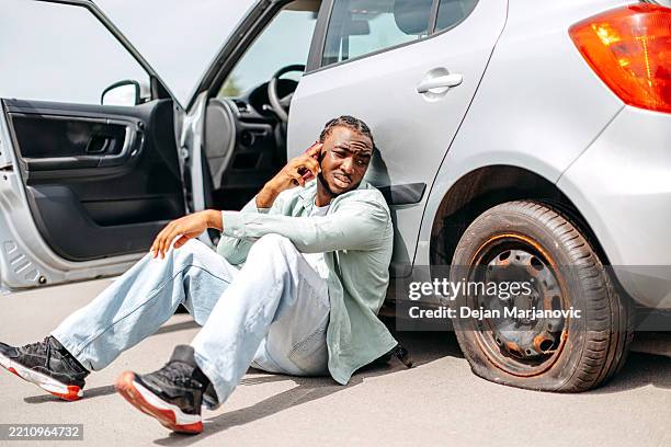 man having flat tyre on his car and using mobile phone to ask for assistance service - flat tyre stock pictures, royalty-free photos & images
