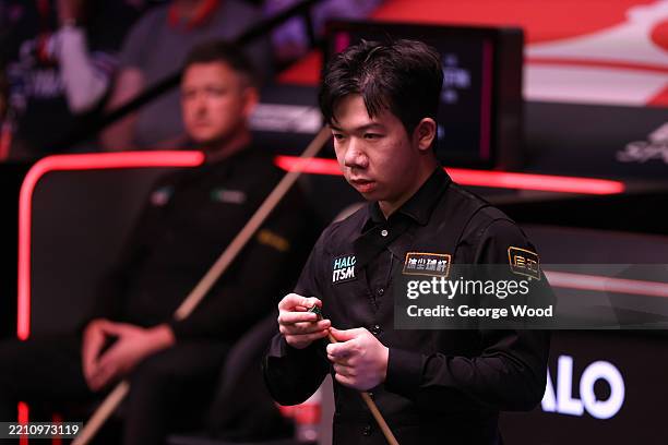 Lei Peifan of China chalks the cue against Kyren Wilson of England on day one of the Halo World Snooker Championship 2025 at Crucible Theatre on...