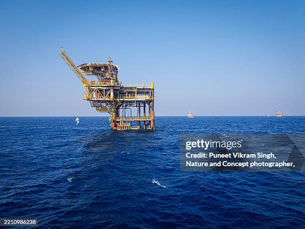 a solitary offshore oil platform stands in the middle of the arabian sea, surrounded by deep blue waters and open ocean. the image captures the scale and isolation of energy infrastructure used in oil and gas exploration in mumbai high fields. - oil production platform stock pictures, royalty-free photos & images