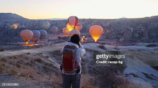photographe masculin et voyageur solitaire capturant le paysage du lever du soleil tôt le matin avec son appareil photo à capadocia - cheminée de fée photos et images de collection
