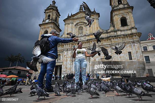 Couple feed pigeons at Plaza Bolivar Square in Bogota on April 23, 2025.