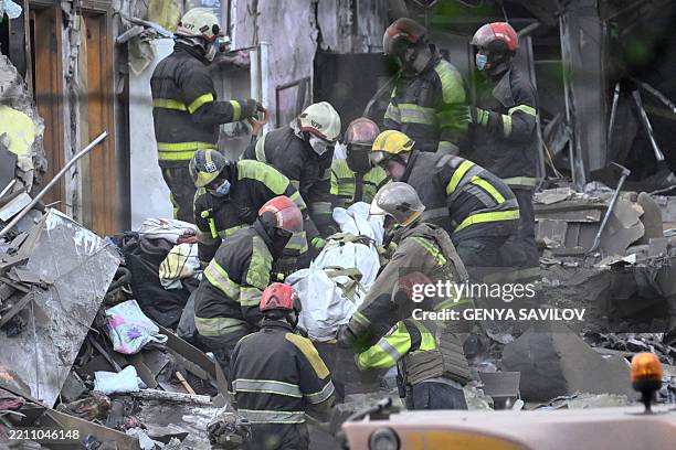 Ukrainian rescuers carry the body of a victim as they operate at the site of a Russian missile attack in Kyiv on April 24 amid the Russian invasion...