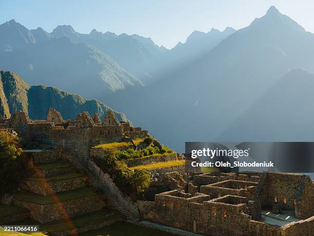 malerischer blick auf machu picchu, der von den strahlen des sonnenaufgangs beleuchtet wird - peru stock-fotos und bilder