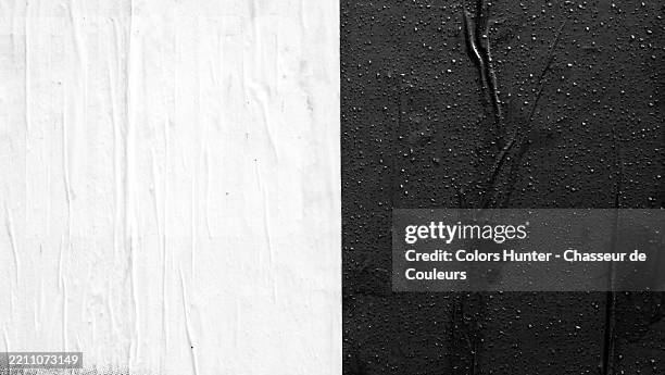black and white papers, glued and wrinkled on a wall, with raindrops. rough texture. sunlight. long island city (queens), new york state, united state. - nat stockfoto's en -beelden