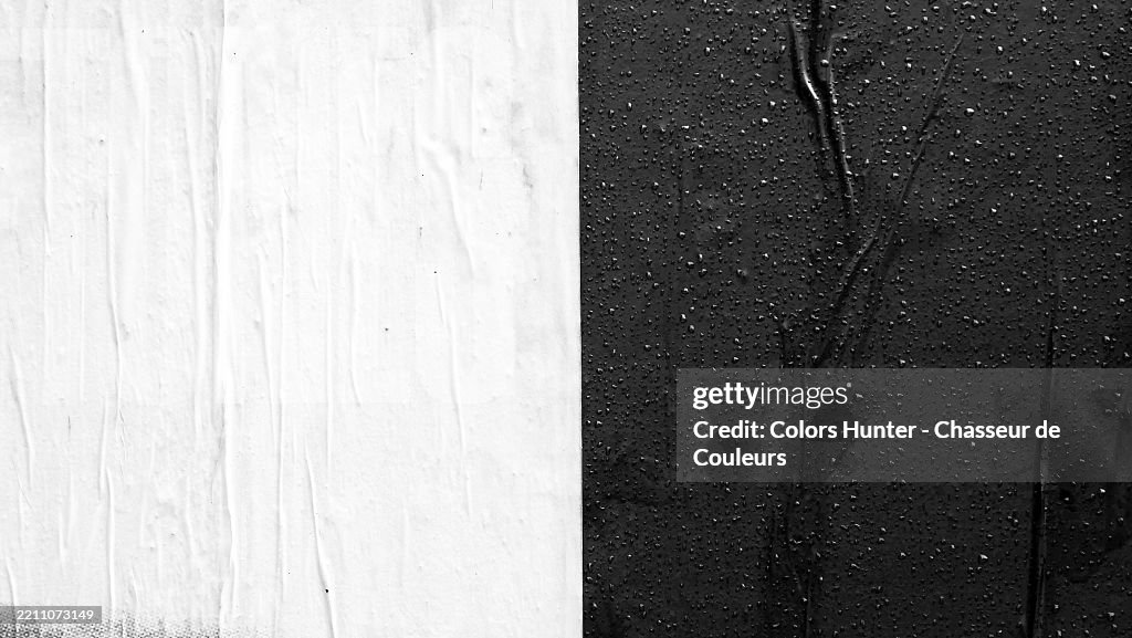 Black and white papers, glued and wrinkled on a wall, with raindrops. Rough texture. Sunlight.
Long Island City (Queens), New York State, United State.