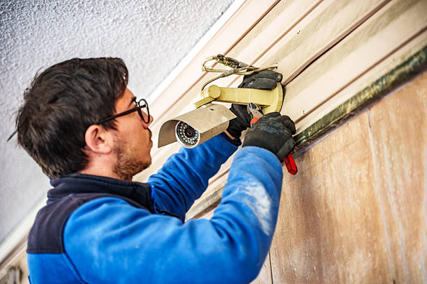 male installer sets up cctv camera outside the apartment block - cctv camera repair stock pictures, royalty-free photos & images