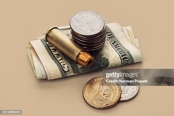 us defense spending - still life of bullet cartridge and quarters on stack of us money bills - gun violence stock pictures, royalty-free photos & images