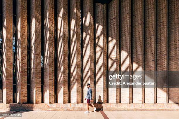 man walking by brick wall on a sunny day - simple living stock pictures, royalty-free photos & images