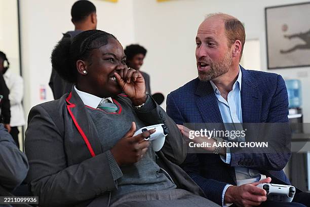 Britain's Prince William, Prince of Wales reacts as he plays a computer game with school children during his visit to the Mentivity community centre...