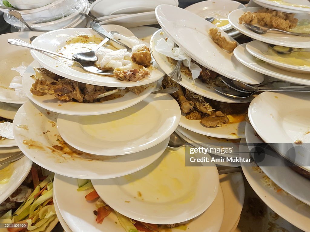 Leftover or wastage of food in dirty cluttered plates and dishes after a party or an event.