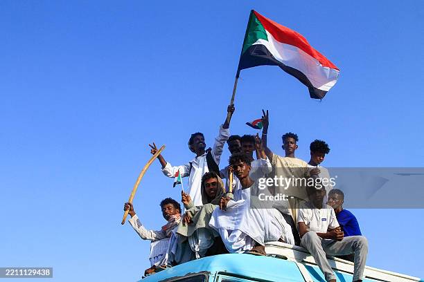 People lift national flags during a rally called for by Sudan's Popular Front for Liberation and Justice in Port Sudan on April 24 to denounce the...