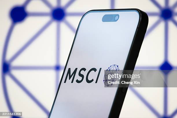In this photo illustration, the logo of MSCI Inc. Is displayed on a smartphone screen, with the company's branding in the background, representing...