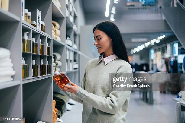 woman shopping for skincare products in modern store interior - toiletries stock pictures, royalty-free photos & images