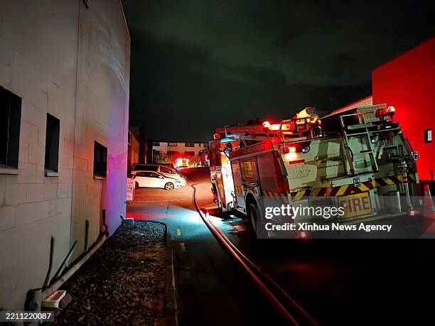 This photo taken with a mobile phone on April 24, 2025 shows a fire engine near the site of a massive fire in Auckland, New Zealand. A massive fire...