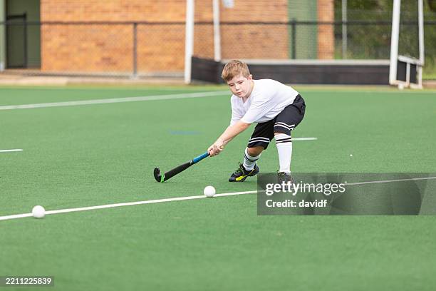 young boy practicing playing field hockey - field hockey stock pictures, royalty-free photos & images