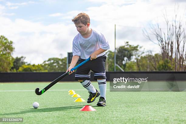 young boy practicing playing field hockey - field hockey stock pictures, royalty-free photos & images
