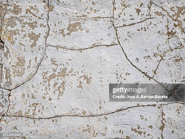 cracks in a white cement wall outside. - adobe material stock pictures, royalty-free photos & images