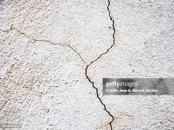 cracks in a white cement wall outside. - adobe material stock pictures, royalty-free photos & images