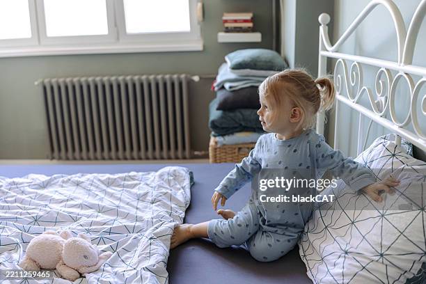 young child in pajamas sitting on bed in cozy bedroom - nightwear stock pictures, royalty-free photos & images