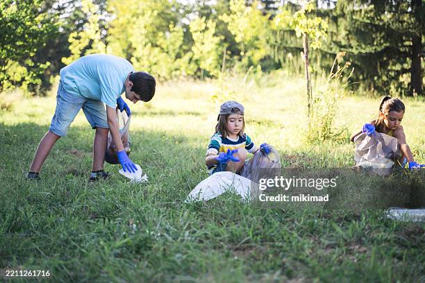 youthful participation in outdoor clean-up initiative - holding garbage bag stock pictures, royalty-free photos & images